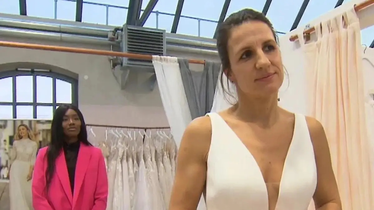 Babett im schlichten Kleid mit tiefem Ausschnitt, im Hintergrund Beraterin Melanie.