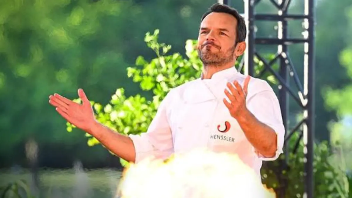 Steffen Henssler hinter einer kleinen Stichflamme.