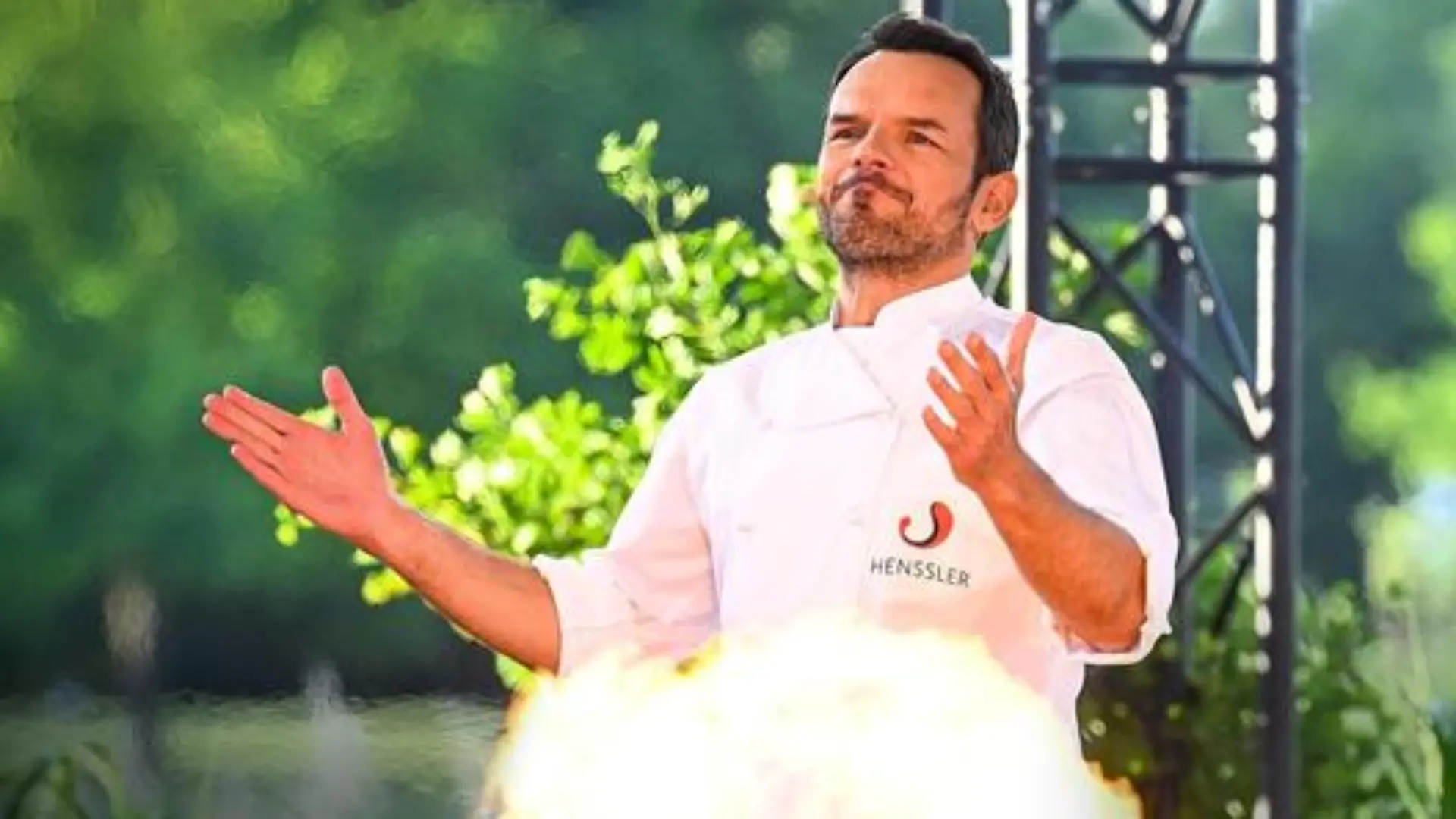 Steffen Henssler hinter einer kleinen Stichflamme.