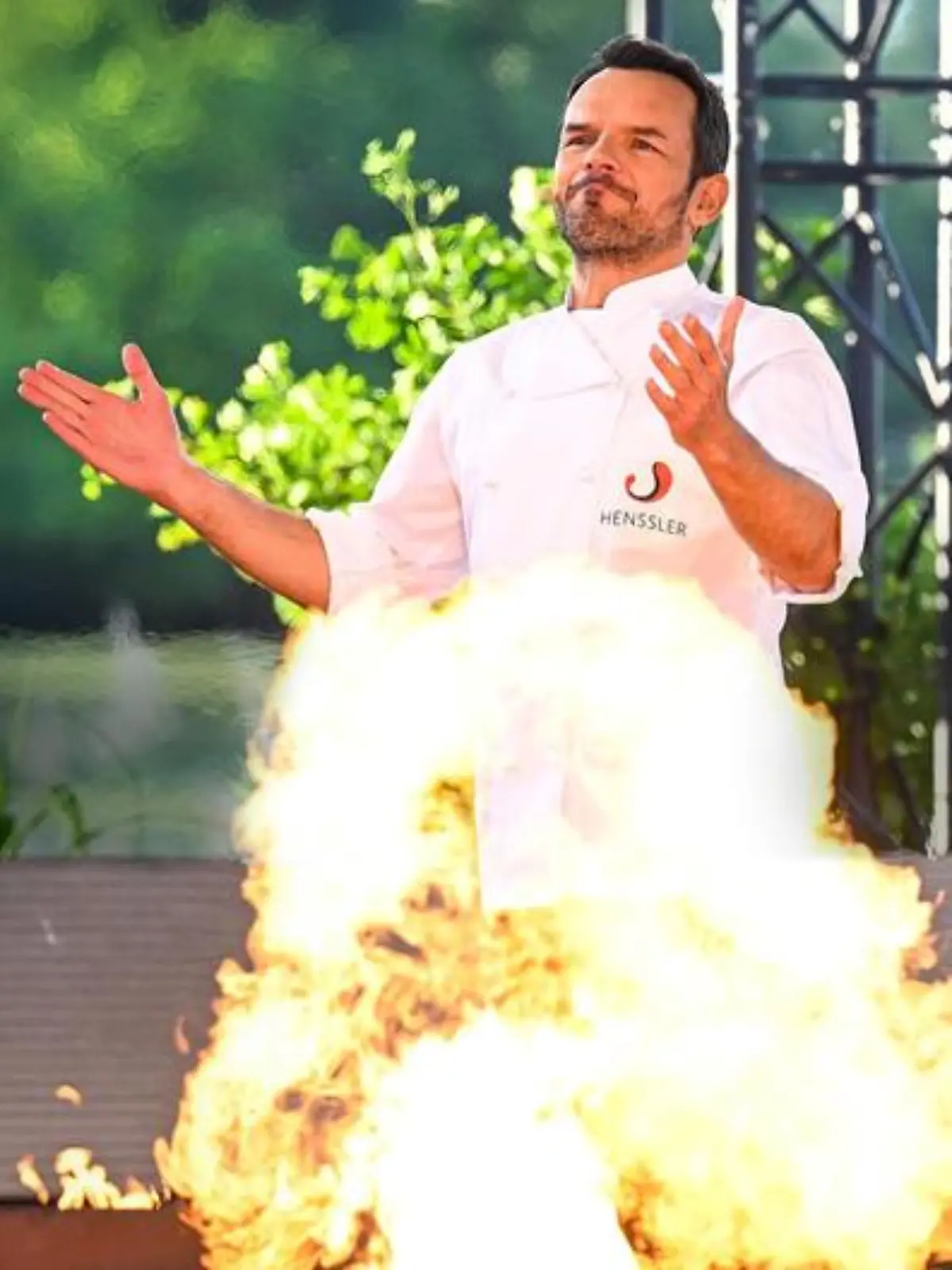 Steffen Henssler hinter einer kleinen Stichflamme.