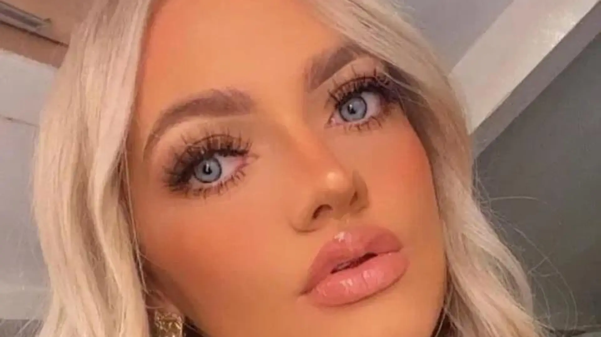 Ein blondes Mädchen mit blauen Augen macht ein Selfie von sich.