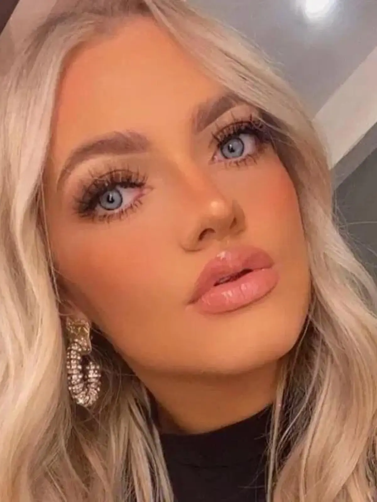 Ein blondes Mädchen mit blauen Augen macht ein Selfie von sich.