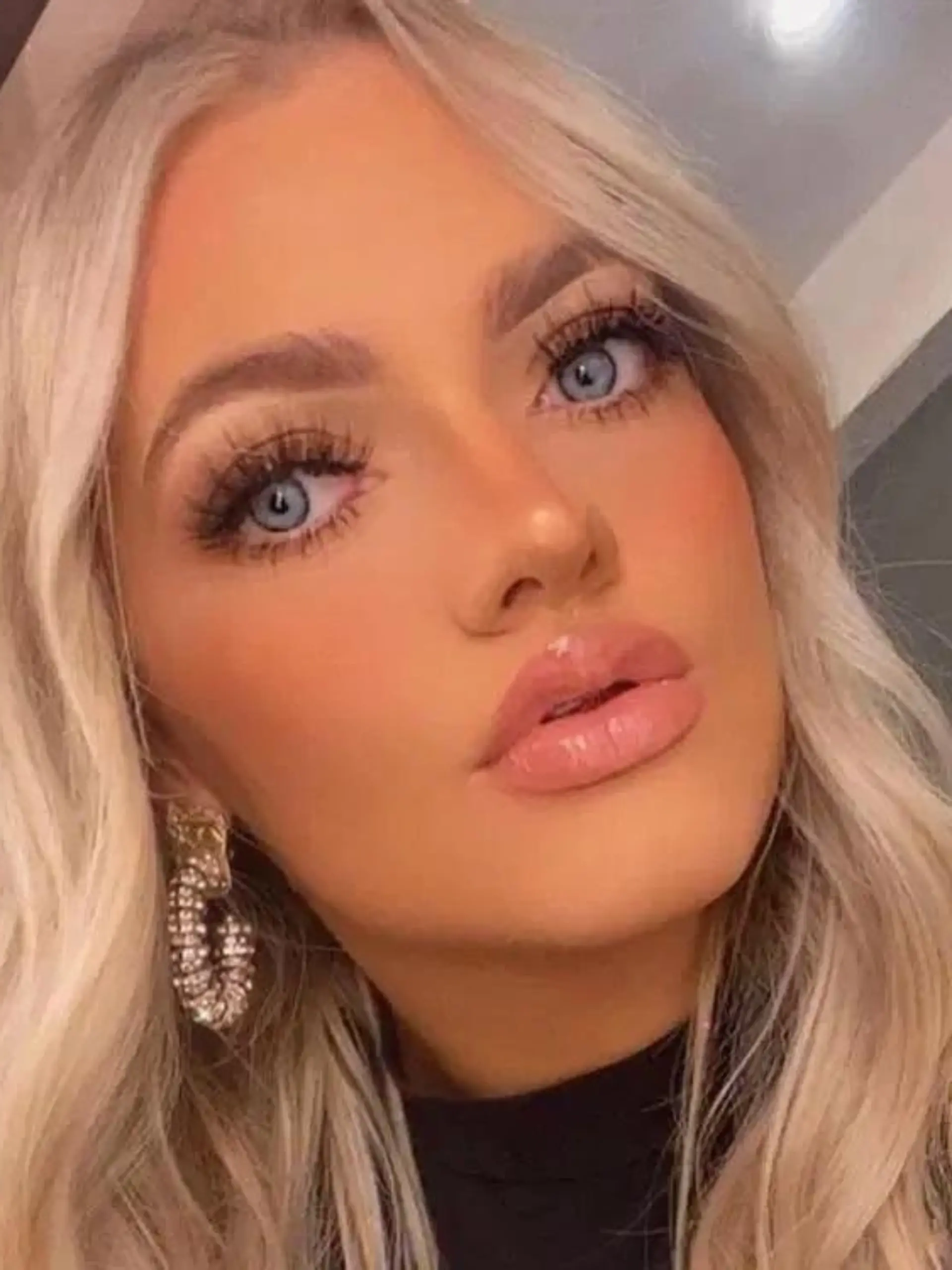 Ein blondes Mädchen mit blauen Augen macht ein Selfie von sich.