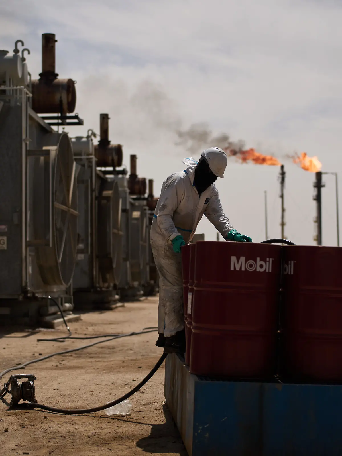 28.03.2026, Irak, Basra: Ein Arbeiter steht an Öltonnen, während er an einer Entgasungsstation im Zubair-Ölfeld in der Nähe von Basra arbeitet. Der Betrieb auf dem Ölfeld ist aufgrund des Iran-Kieges eingeschränkt. Foto: Leo Correa/AP/dpa +++ dpa-Bildfunk +++
