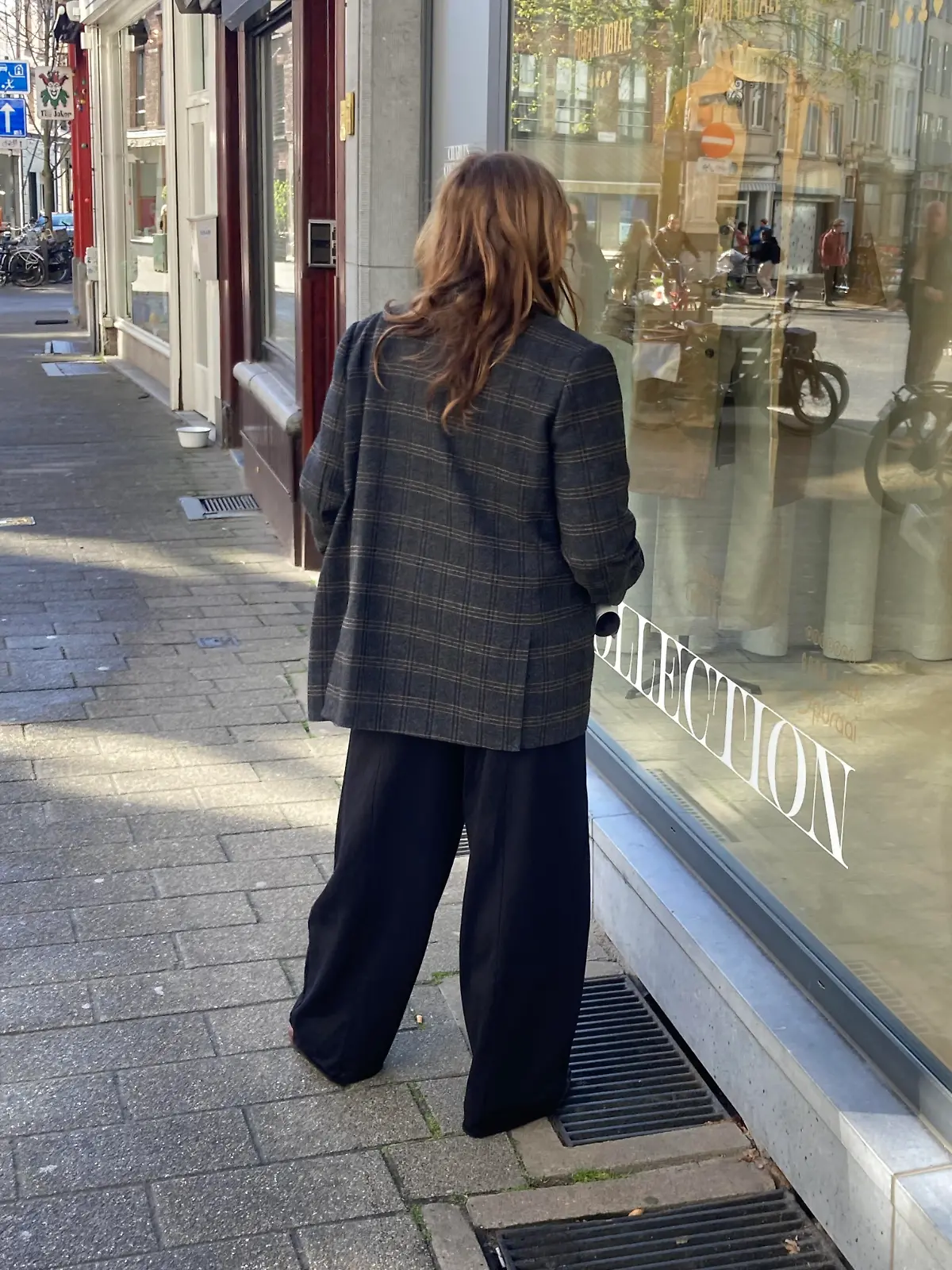 Eine Frau in Kleidung im Oversize-Look vor einem Schaufenster. Warum tragen wir heute Oversize? (zu dpa: «Groß, weit, schlabberig: Warum tragen wir heute Oversize?») +++ dpa-Bildfunk +++