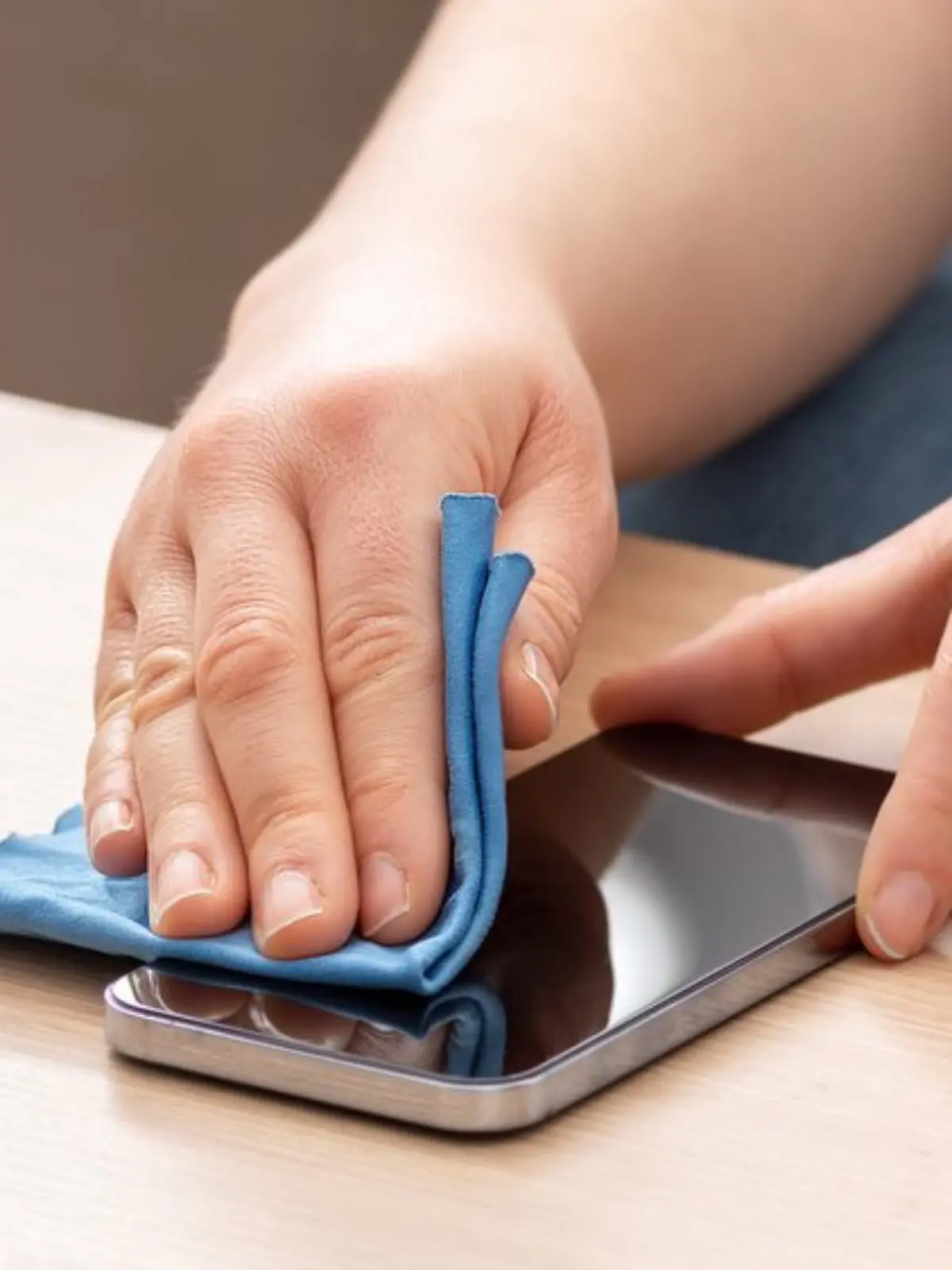 Person reinigt Handy-Display vorsichtig mit einem Brillentuch, das Kratzern vorbeugt.