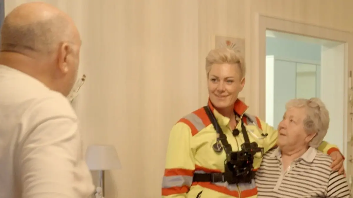 Ärztin Arm in Arm mit einer älteren Frau, die freundlich zu ihr aufblickt.