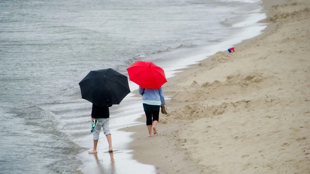 Touristen laufen im Regen am 20.08.2014 am Strand des Seebades Zinnowitz auf der Insel Usedom (Mecklenburg-Vorpommern). Die Meteorologen erwarten auch in den kommenden Tagen wechselhaftes Wetter an der Ostsee. Foto: Stefan Sauer/dpa +++(c) dpa - Bildfunk+++