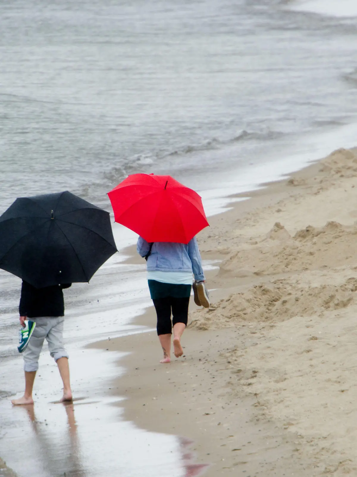 Touristen laufen im Regen am 20.08.2014 am Strand des Seebades Zinnowitz auf der Insel Usedom (Mecklenburg-Vorpommern). Die Meteorologen erwarten auch in den kommenden Tagen wechselhaftes Wetter an der Ostsee. Foto: Stefan Sauer/dpa +++(c) dpa - Bildfunk+++