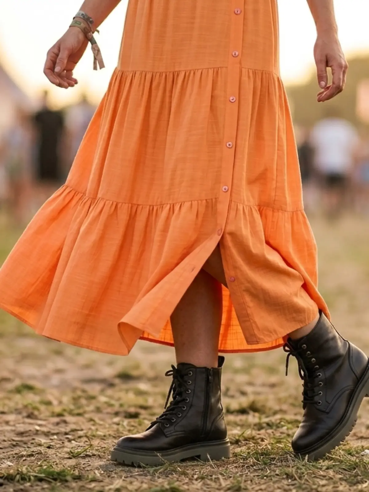 Frau trägt einen orangefarbenen Maxi-Rock auf einem Festival.