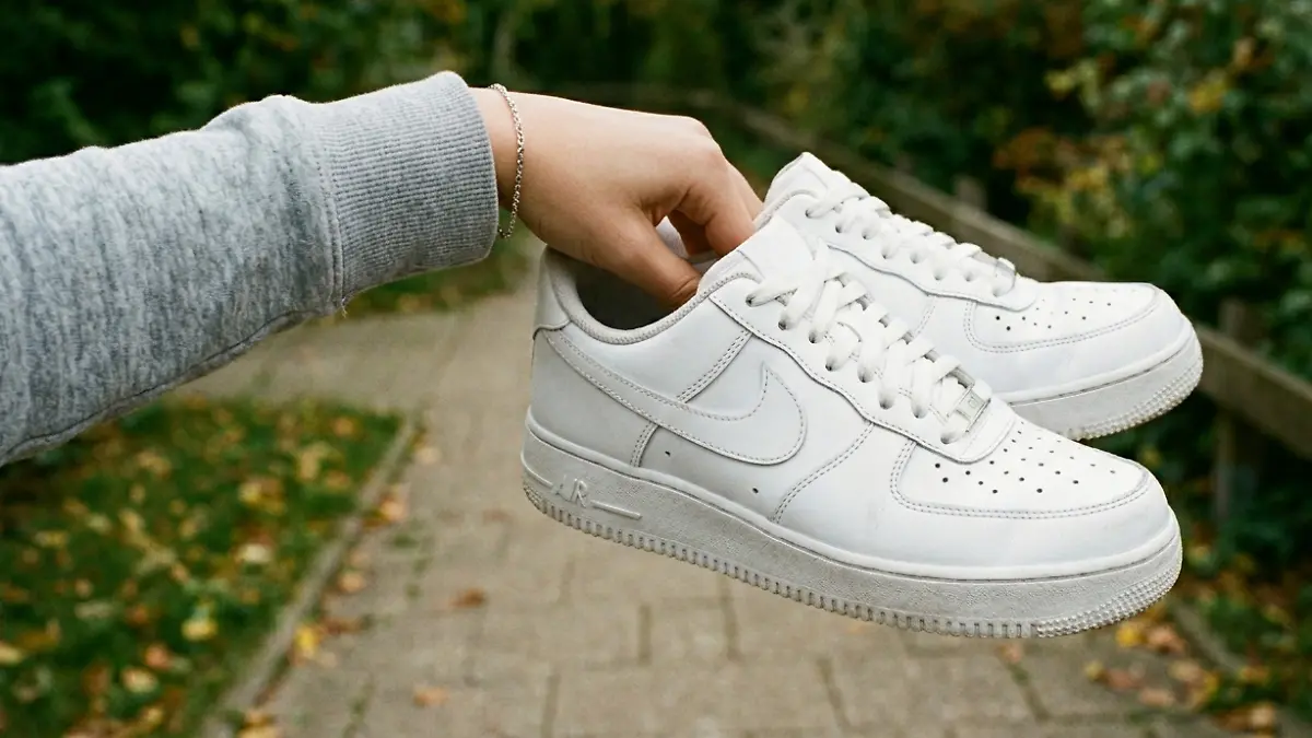 Frau hält ein Paar Nike Air Force 1 in die Kamera.
