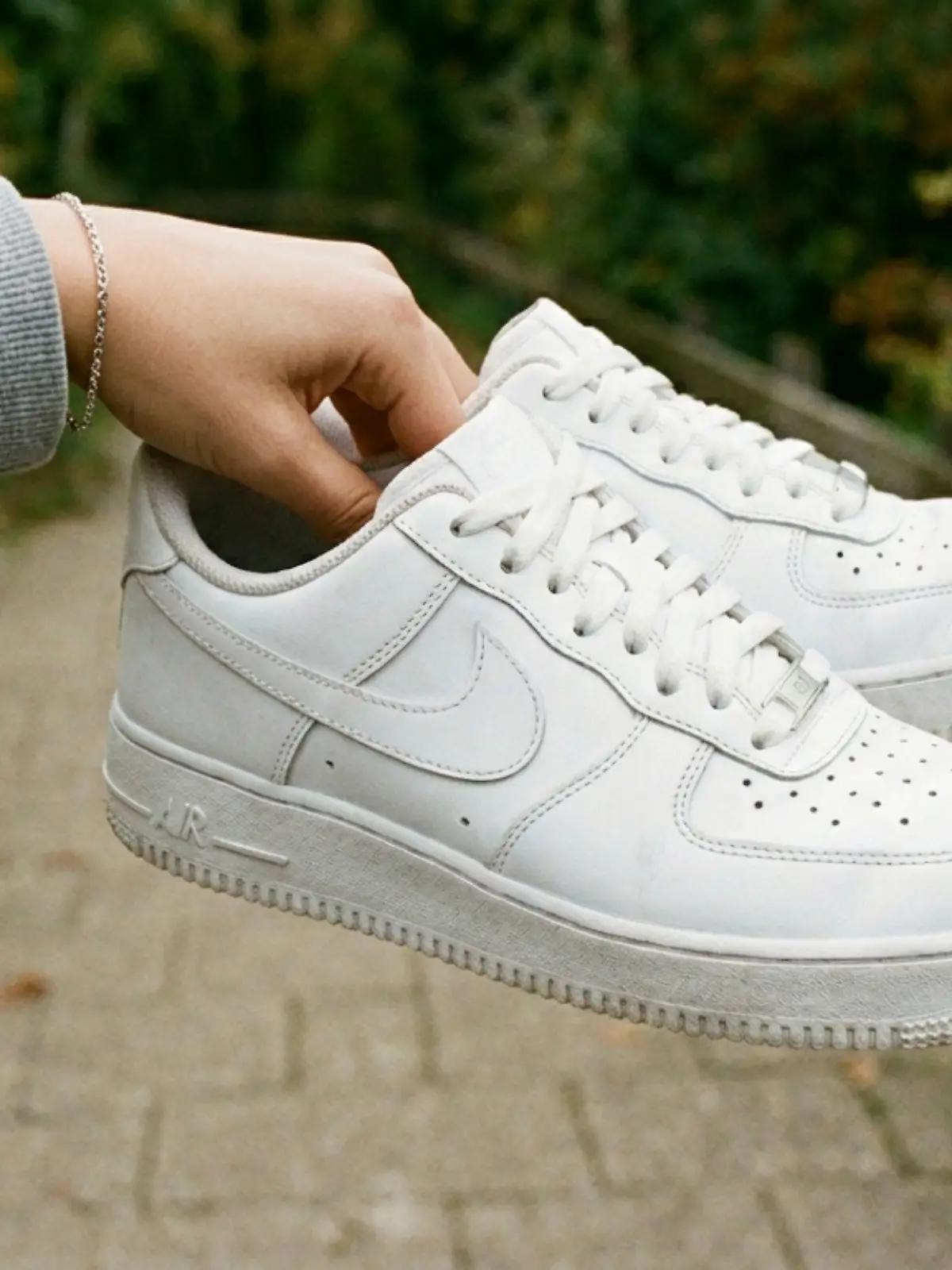 Frau hält ein Paar Nike Air Force 1 in die Kamera.