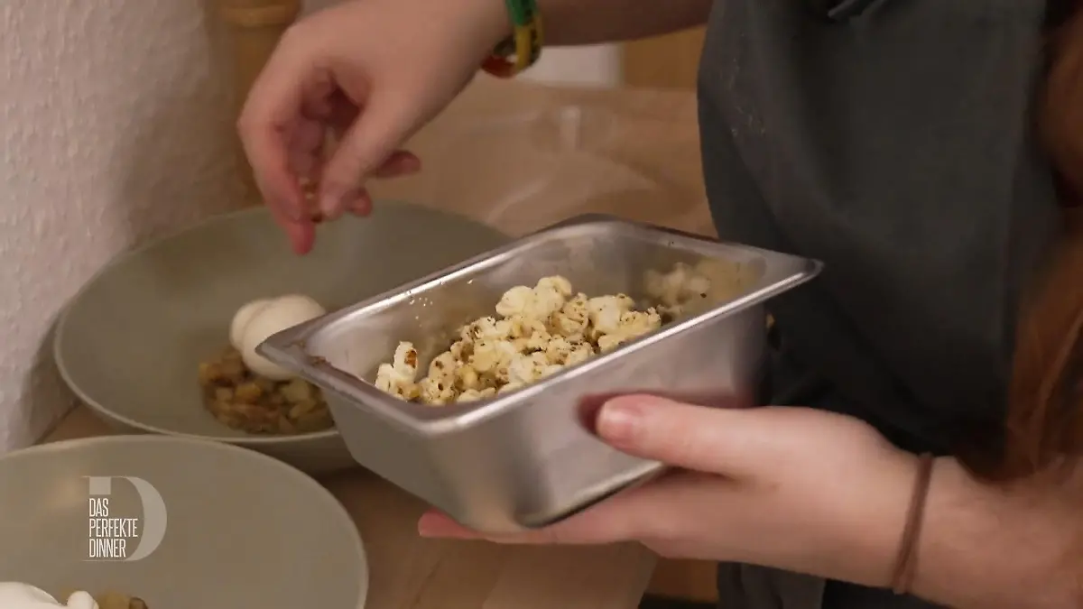 Popcorn, das aus einem Behälter über die Vorspeise gestreut wird.