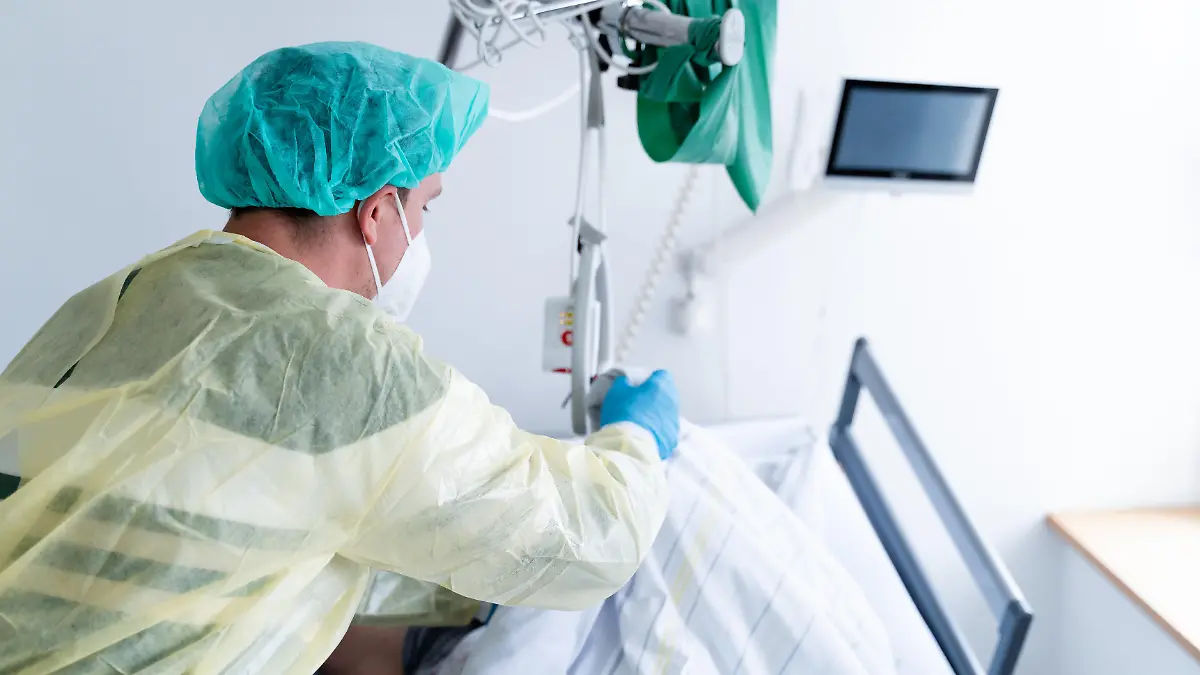 Eine Pflegekraft steht am Krankenbett einer schwerkranken Patientin im Krankenhaus. Symbolfoto thematisiert Sterben, palliative Begleitung und den würdevollen Umgang mit dem Lebensende im klinischen Pflegealltag