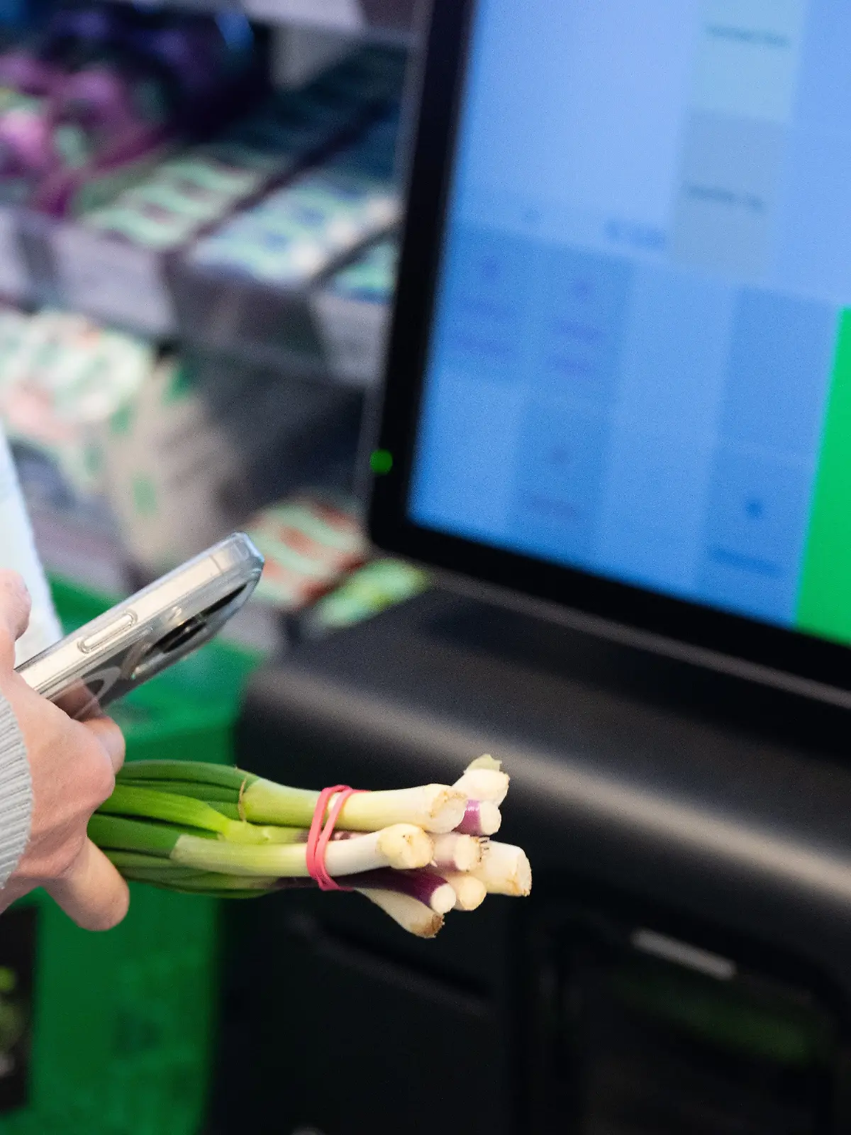 Eine Kundin bezahlt an einer SB-Kasse mit einem Smartphone.