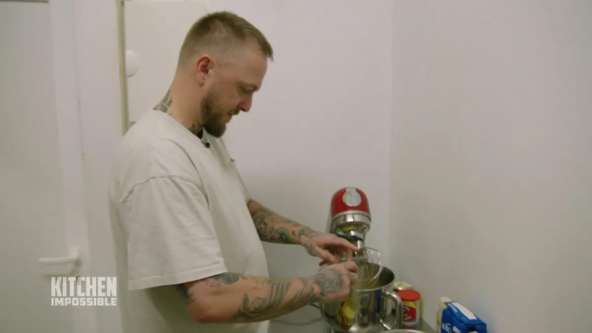 Koch Cozy schlägt ein Ei in einer Küchenmaschine auf.