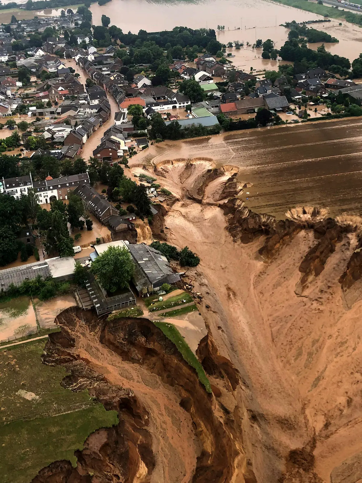 This image provided on Friday, July 16, 2021 by the Cologne district government shows the Blessem district of Erftstadt in Germany. Rescuers were rushing Friday to help people trapped in their homes in the town of Erftstadt, southwest of Cologne. Regional authorities said several people had died after their houses collapsed due to subsidence, and aerial pictures showed what appeared to be a massive sinkhole.(Rhein-Erft-Kreis via AP)