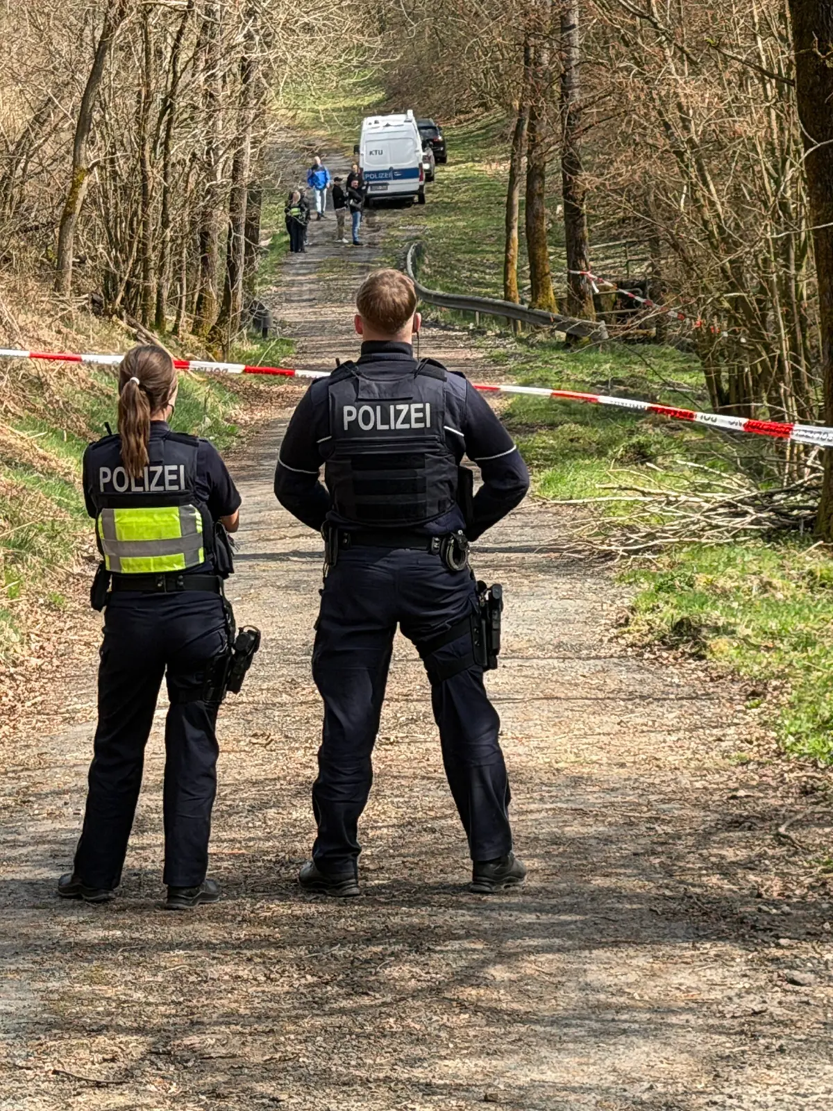 Kräfte der Polizei sind in einem mit Flatterband abgesperrten Bereich eines Waldes im Einsatz. Bei einer Müllsammelaktion wurde unweit der A4 ein menschlicher Kopf gefunden. +++ dpa-Bildfunk +++