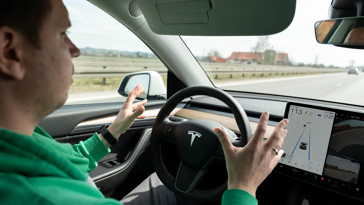 Konzept - Autonomes Fahren im Alltag - Ein Fahrer sitzt entspannt im Auto mit aktivem Assistenzsystem von Tesla und Händen weg vom Lenkrad, während das Fahrzeug mit Kamera selbstständig fährt und die Entwicklung moderner Mobilität und Technologie zeigt.