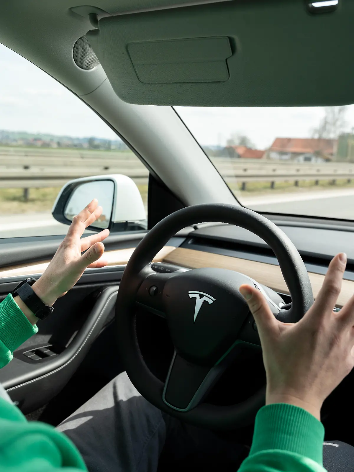 Konzept - Autonomes Fahren im Alltag - Ein Fahrer sitzt entspannt im Auto mit aktivem Assistenzsystem von Tesla und Händen weg vom Lenkrad, während das Fahrzeug mit Kamera selbstständig fährt und die Entwicklung moderner Mobilität und Technologie zeigt.