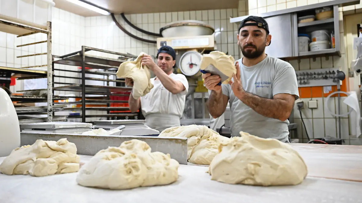 PRODUKTION - 11.12.2025, Hessen, Nidderau-Windecken: Die Bäcker Subhan Ullah (l) und Sulaiman Shapal kneten Teig in einer Backstube. Beide sind als Migranten aus Afghanistan und Syrien nach Deutschland gekommen. (zu dpa: «Migranten schließen Lücken in Hessens Bäckereien») Foto: Michael Brandt/dpa +++ dpa-Bildfunk +++