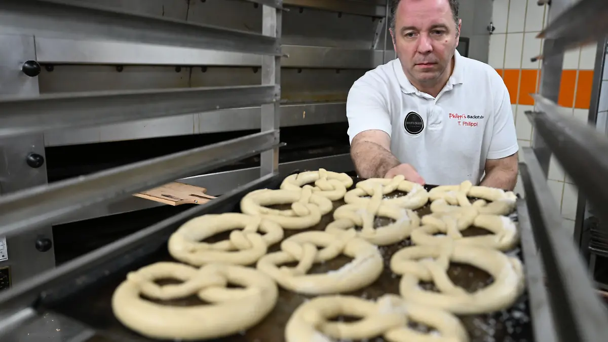 PRODUKTION - 11.12.2025, Hessen, Nidderau-Windecken: Bäckermeister Thorsten Philippi schiebt Brezelteig auf einen Wagen in einer Backstube. (zu dpa: «Migranten schließen Lücken in Hessens Bäckereien») Foto: Michael Brandt/dpa +++ dpa-Bildfunk +++