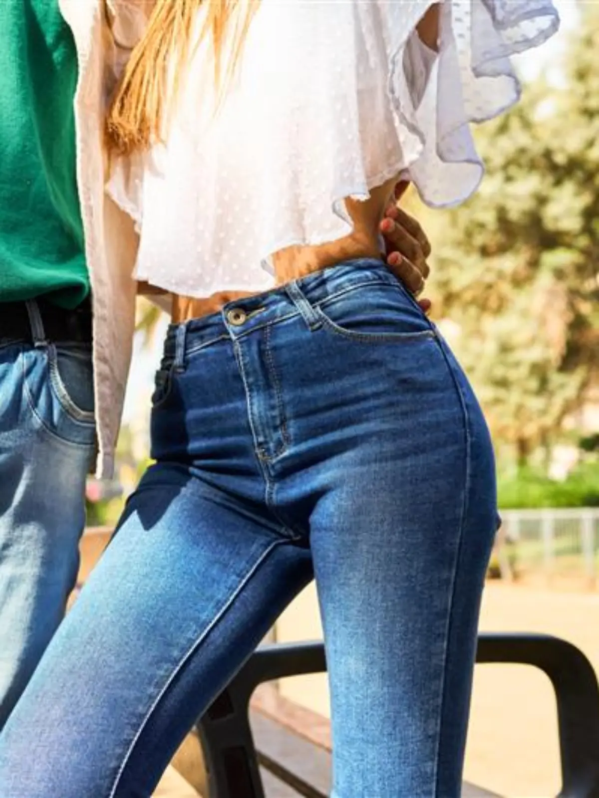 Mann mit Jeans und Hemd legt den Arm um eine Frau in enger Jeans und Boho-Bluse.