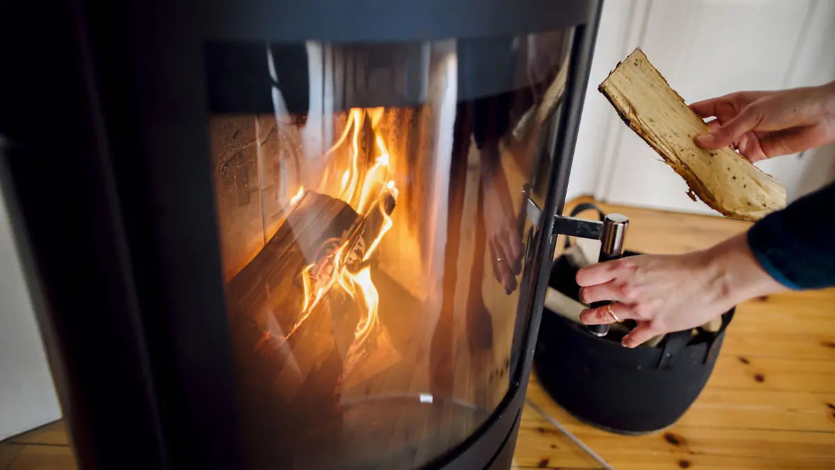 Symbolfoto: Eine Frau wirft ein Holzscheit in einen Kaminofen. Berlin, 03.03.2023 || Modellfreigabe vorhanden