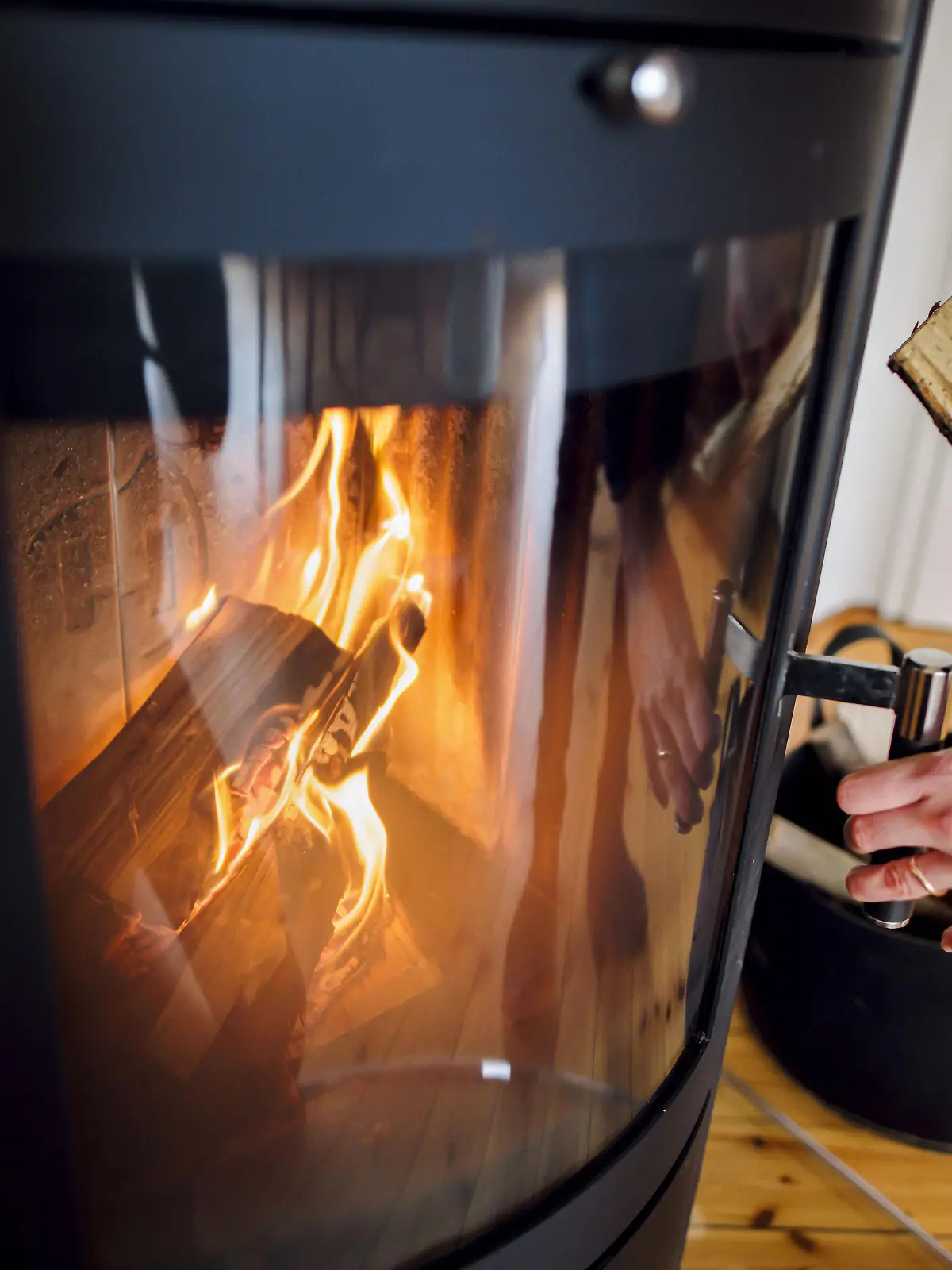 Symbolfoto: Eine Frau wirft ein Holzscheit in einen Kaminofen. Berlin, 03.03.2023 || Modellfreigabe vorhanden