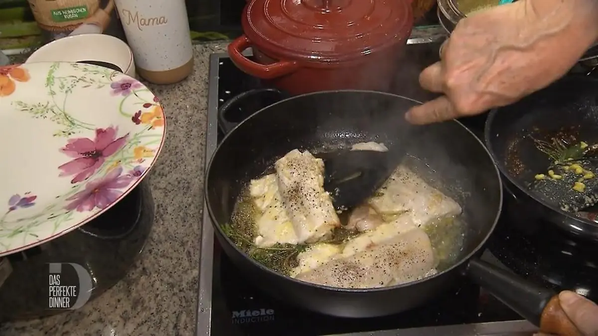 Noch sehr roher Zander brät mit Kräutern und Gewürzen in der Pfanne.