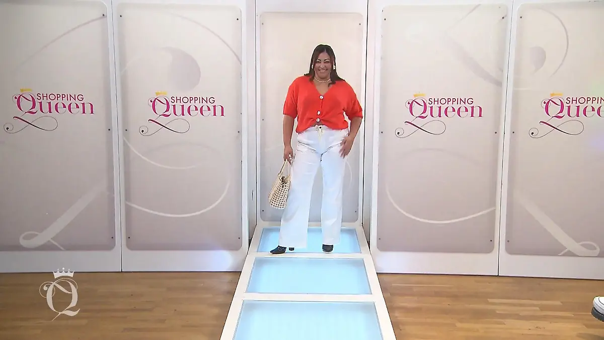 Shopping Queen: Junge dunkelhäutige Frau mit langen dunklen Haaren, lachsfarbenem Oberteil, weißer Hose und durchbrochener Tasche auf dem Laufsteg