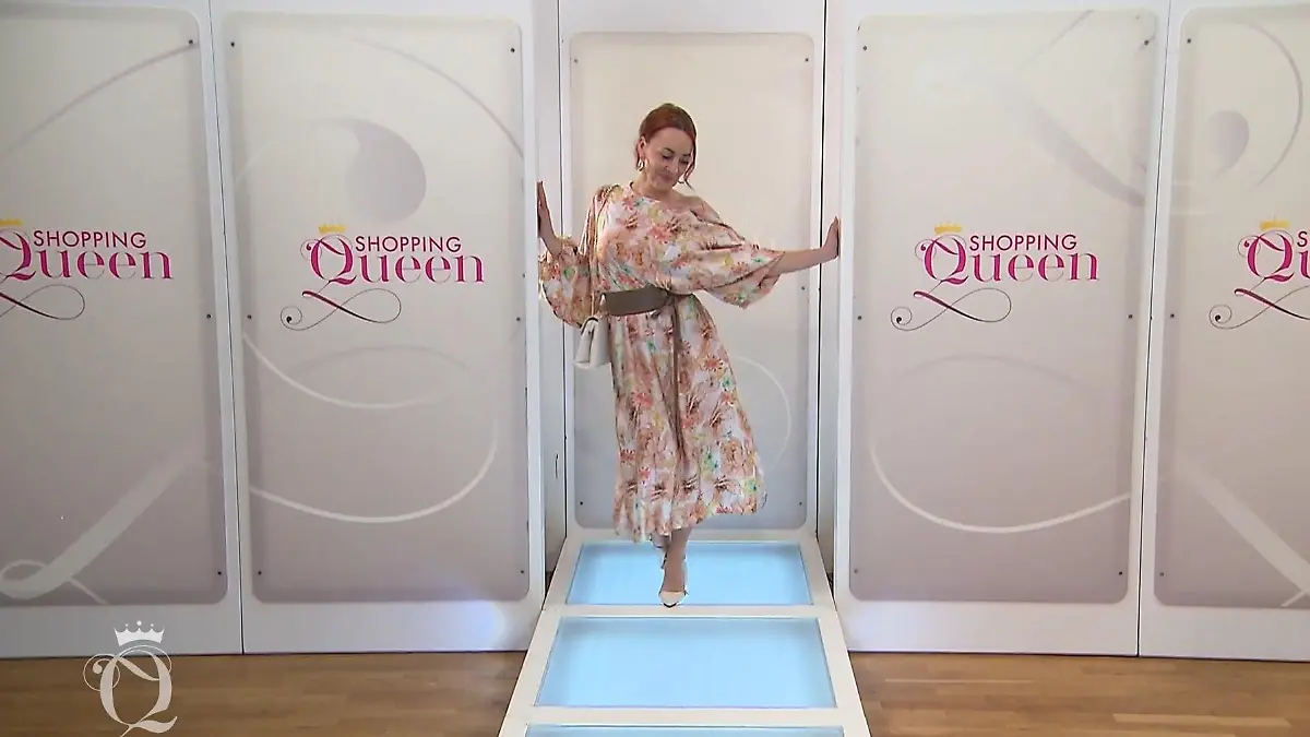 Shopping Queen: Kandidatin Viktoria in einem weiten, floral bedruckten Kleid mit braunem Gürtel und weißer Handtasche und Schuhen auf dem Catwalk