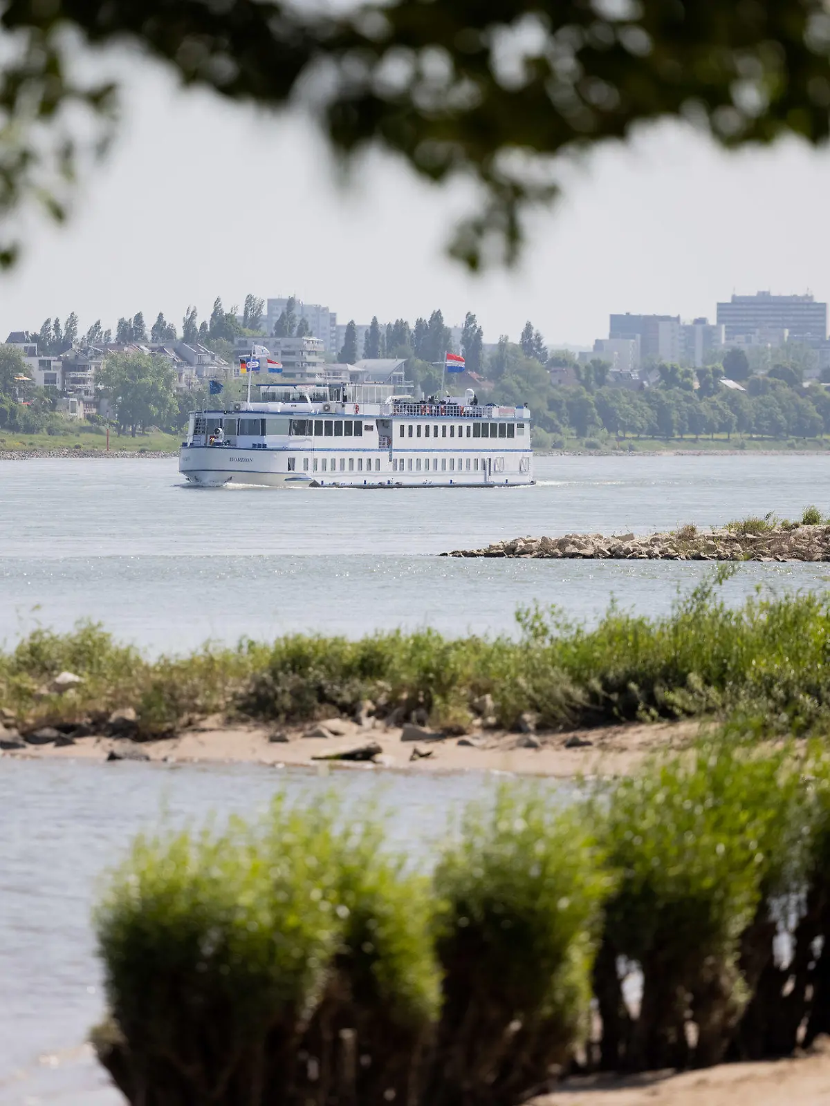 30.05.2023, Nordrhein-Westfalen, Köln: Eine Mann und sein Hund gehen bei Sonnenschein im Sand am Rhein in Rodenkirchen spazieren. Laut dem Deutschen Wetterdienst, soll das Wetter in den nächsten Tagen sonnig bei Temperaturen über 20°C bleiben. Foto: Rolf Vennenbernd/dpa +++ dpa-Bildfunk +++