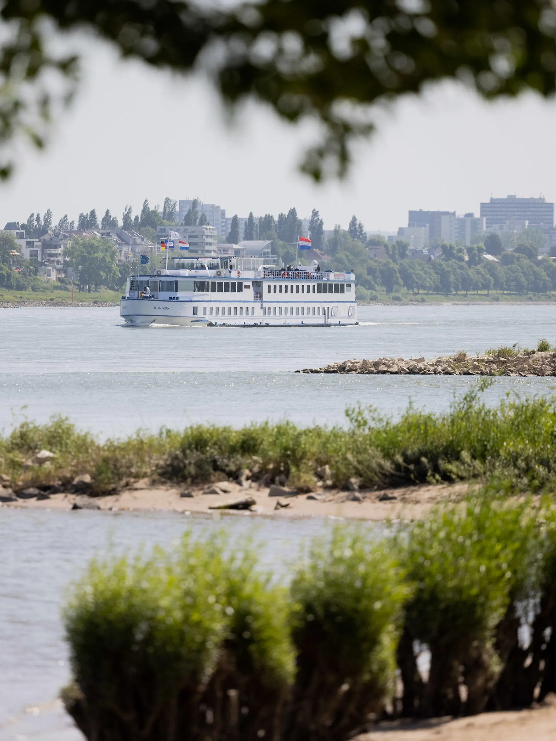 30.05.2023, Nordrhein-Westfalen, Köln: Eine Mann und sein Hund gehen bei Sonnenschein im Sand am Rhein in Rodenkirchen spazieren. Laut dem Deutschen Wetterdienst, soll das Wetter in den nächsten Tagen sonnig bei Temperaturen über 20°C bleiben. Foto: Rolf Vennenbernd/dpa +++ dpa-Bildfunk +++