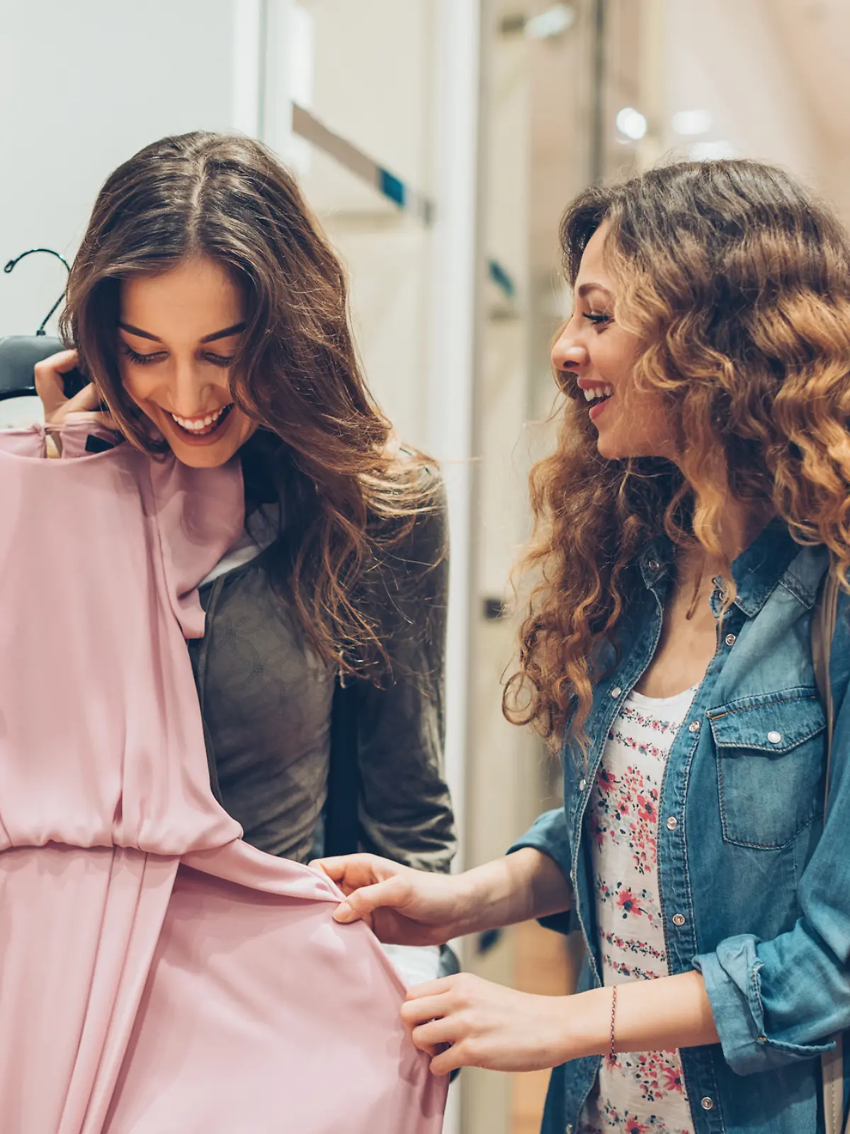 Zwei Frauen sind in einem Kleidungsgeschäft und suchen Kleider aus.