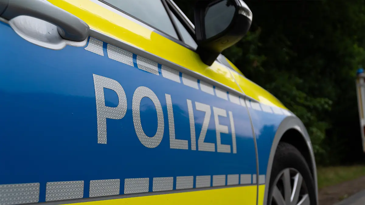 Landkreis Osnabrück, Deutschland 10. Juni 2025: Im Bild: Caption: Nahaufnahme des Seitenbereichs eines deutschen Polizeifahrzeugs mit dem markanten silberfarbenen "POLIZEI"-Schriftzug auf blauem Grund. Der Schriftzug ist auf einer reflektierenden Folie angebracht, die für erhöhte Sichtbarkeit sorgt. Auffällig ist die leuchtend gelbe Kontrastfarbe, die sich von der Motorhaube bis zur Tür zieht und von einer Reihe reflektierender Quadrate begleitet wird. Details wie der Türgriff und der Außenspiegel sind im oberen Bereich des Bildes erkennbar. Das Bild repräsentiert die Präsenz und den modernen Auftritt der deutschen Polizei.