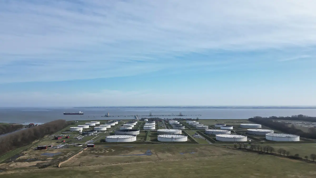 Ein Öltanker liegt an der Tankerlöschbrücke der Nord-West Oelleitung (NWO) auf der Jade bei Wilhelmshaven, im Vordergrund stehen große Lagertanks eines Mineralöltanklagers. (Luftaufnahme mit einer Drohne) Über Hafenanlagen, Pipelines und Tanklager werden Rohöl und Mineralölprodukte angeliefert, gespeichert und weitertransportiert; die Infrastruktur ist Teil der Energieversorgung in Deutschland.