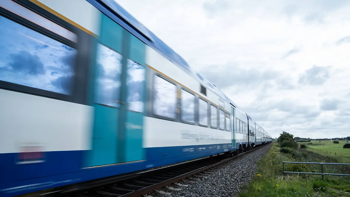 Regionalexpress RE6 zwischen auf der Strecke zwischen den Endbahnhöfen Westerland und Hamburg-AltonaBahnstrecke der Marschbahn auf der Nordseeinsel Sylt am Bahnübergang BÜ 155 Raitkoog nahe dem Ort Achsum Zug auf dem Abschnitt zwischen den Orten Westerland und Niebüll kurz vor dem Hindenburgdamm, Sylt Schleswig-Holstein Deutschland Achsum *** Regional express RE6 between on the route between the terminus stations Westerland and Hamburg Altona Railway line of the Marschbahn on the North Sea island of Sylt at level crossing BÜ 155 Raitkoog near the village of Achsum Train on the section between the villages of Westerland and Niebüll shortly before Hindenburgdamm, Sylt Schleswig Holstein Germany Achsum