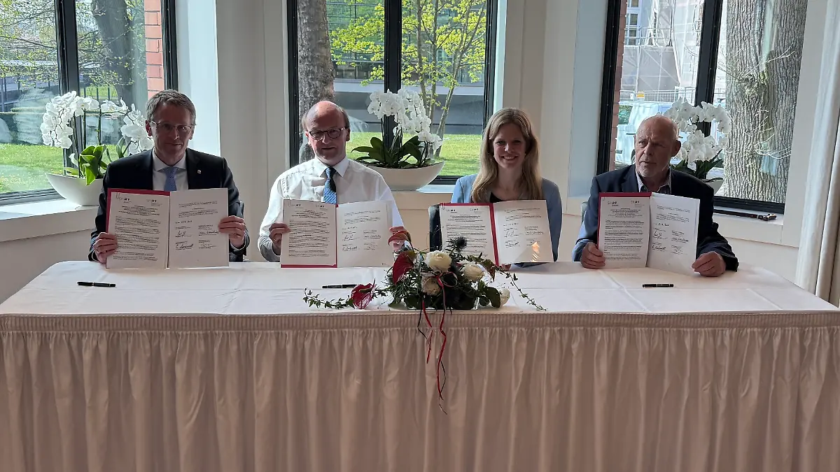 Politiker und Fischer halten die unterschriebene Vereinbarung in die Kamera.