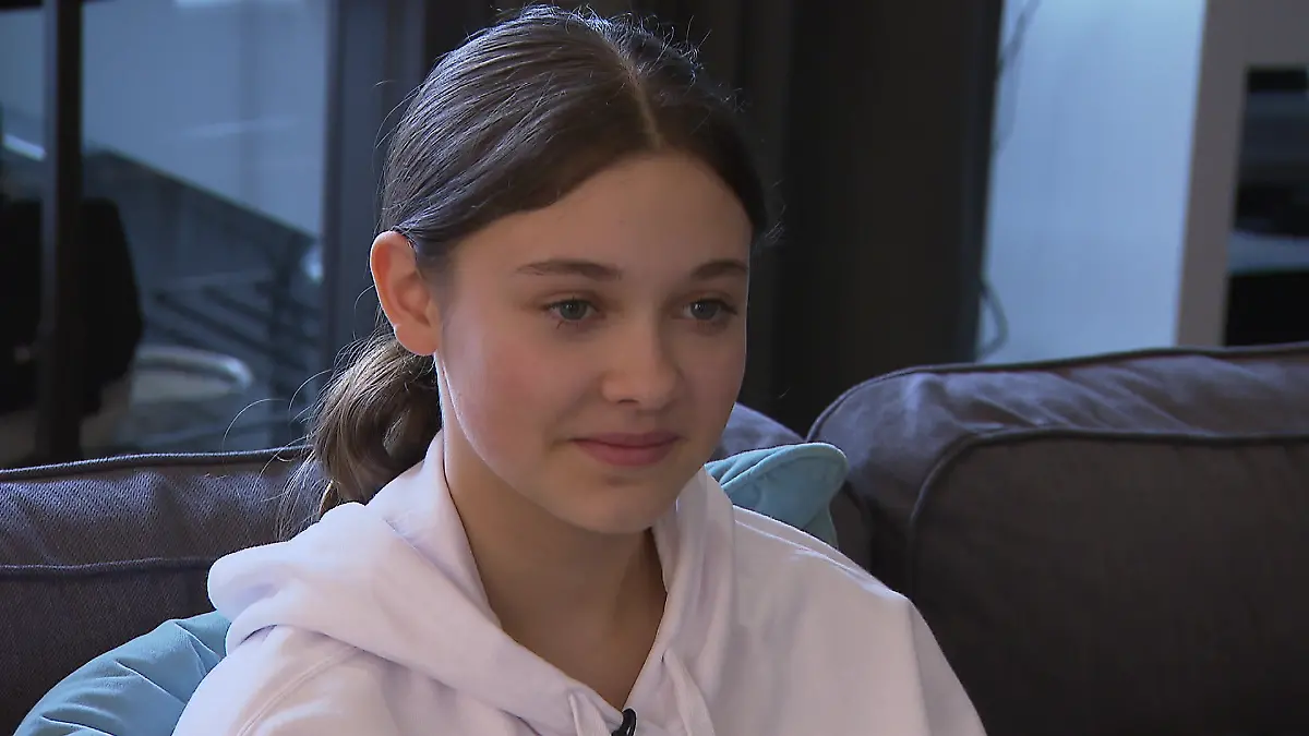 Zwischen Tüll und Tränen: Junges Mädchen mit langen braunen Haaren und einem roséfarbenen Hoodie in Nahaufnahme