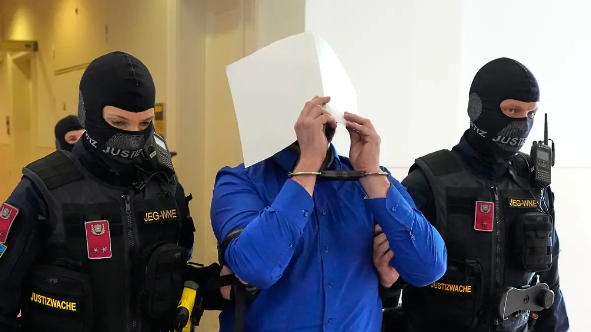 Defendant Beran A. is hiding his face behind file folders when he is escorted out of the courtroom in the District Court in Wiener Neustadt, Austria, where he stands trial for plotting to carry out an attack on one of superstar singer Taylor Swift's concerts in Vienna in August 2024 and pledging allegiance to the Islamic State group, Tuesday, April 28, 2026. (AP Photo/Matthias Schrader)
