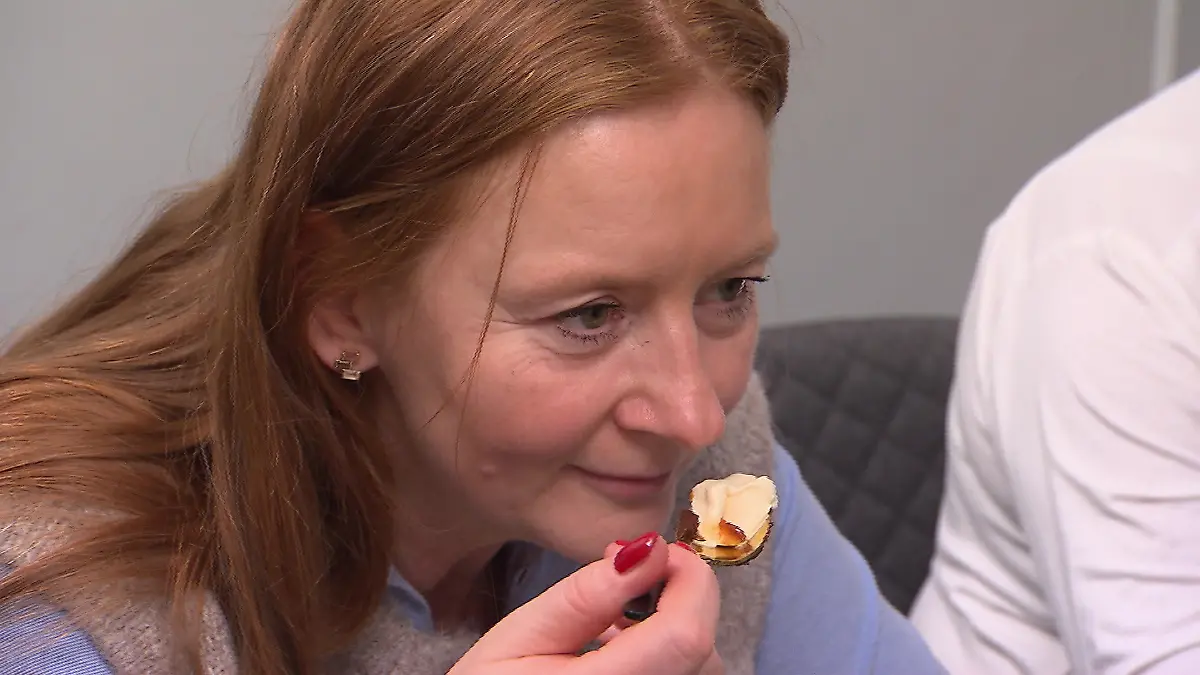 Das perfekte Dinner: Frau führt genießerisch einen kleinen Löffel mit Dessert an den Mund.