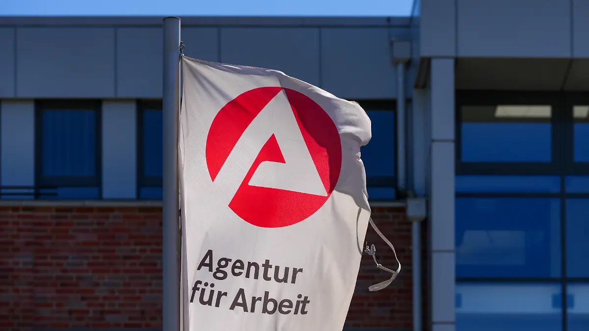 Eine Flagge mit dem Logo der Arbeitsagentur und dem Schriftzug «Agentur für Arbeit» weht an der Einfahrt in der Straße Horstweg.