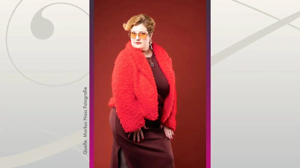 Shopping Queen: Junge Frau mit kurzen Haaren im bordeauxfarbenen engen Kleid, darüber eine knallrote Fakefur-Jacke. An den Füßen trägt sie schwarze Lack-Gummistiefel