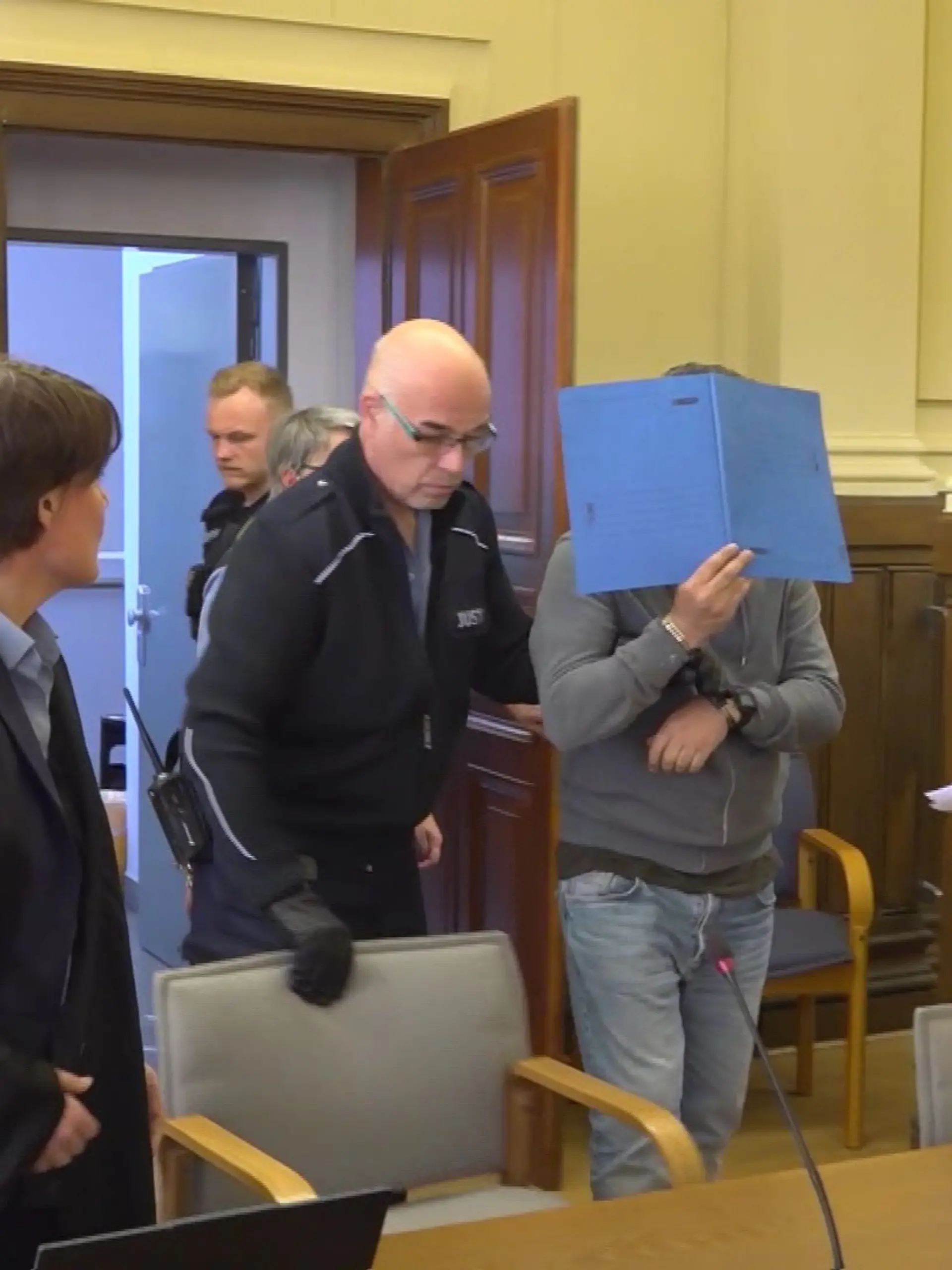 Kemal A. (mit Aktenmappe in der Mitte) steht wegen eines Messerangriffs vor Gericht