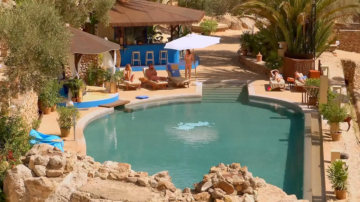 Poollandschaft mit Plamen und Liegen.
