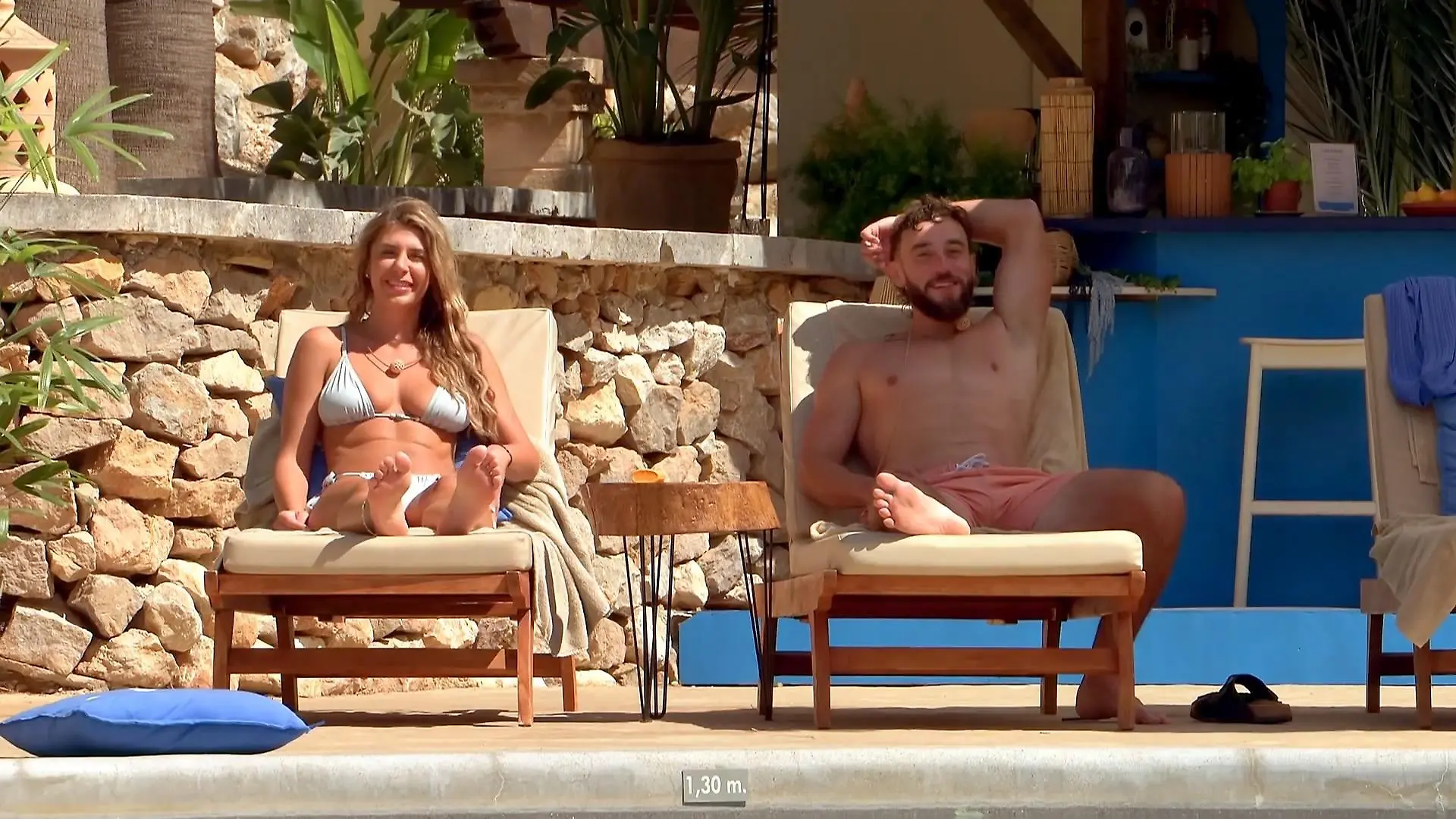 Tamara und Phillip auf zwei Liegen am Pool.