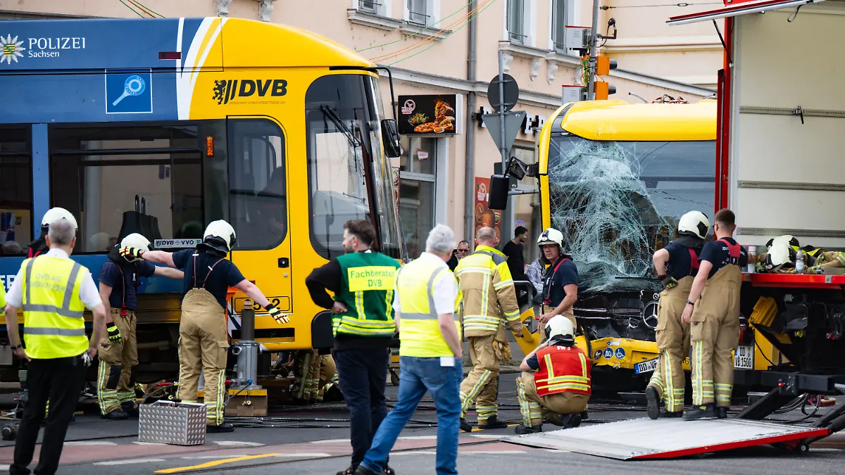 Feuerwehrleute arbeiten daran, eine Straßenbahn der Dresdner Verkehrsbetriebe (DVB) nach einem Zusammenstoß mit einem Bus in die Gleise zu heben. Bei einem Zusammenstoß zwischen einer Straßenbahn und einem Linienbus in Dresden sind rund 30 Menschen verletzt worden. +++ dpa-Bildfunk +++