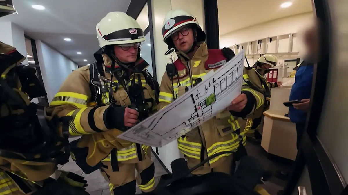 Zwei Feuerwehrmänner der Feuerwache 1 in Köln sehen sich den Plan des Krankenhauses an.