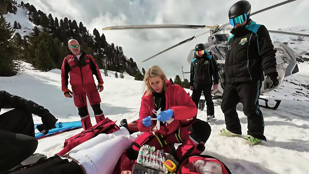 Ärztin Dr. Susanne Wally versorgt die Patientin am Zwischenlandeplatz, dahinter der Helicopter Martin 7 und die Pistenretter aus Mayrhofen.